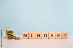 For business mindset concept, MINDSET text on wooden cube blocks with blurred coins in jar including copy space